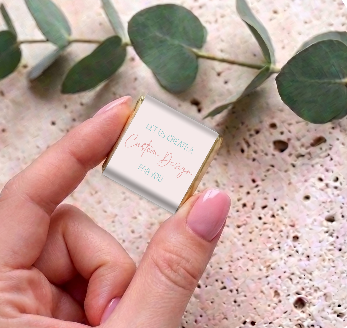 Hand holding a mini chocolate square with white custom message card and gold foil sides