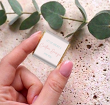 Hand holding a mini chocolate square with white custom message card and gold foil sides