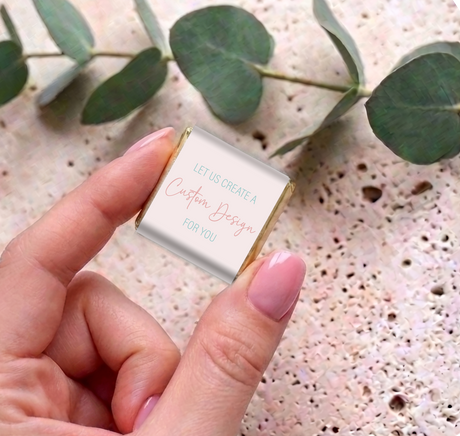 Hand holding a mini chocolate square with white custom message card and gold foil sides
