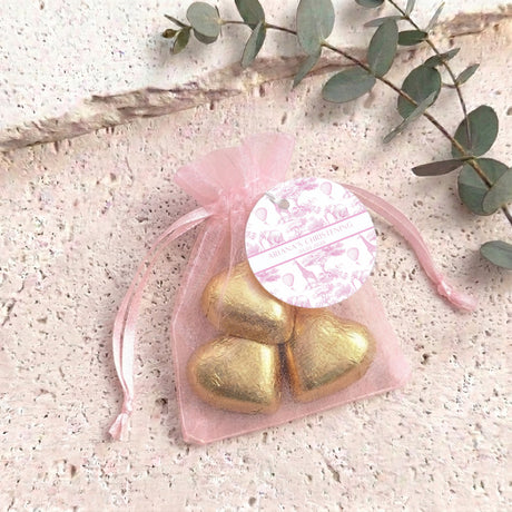 Personalized organza christening bag with round label and gold metallic heart chocolates