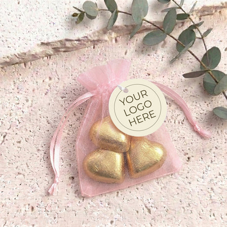 Light pink organza drawstring bag with gold heart chocolates and white 'YOUR GO GO HERE' tag.
