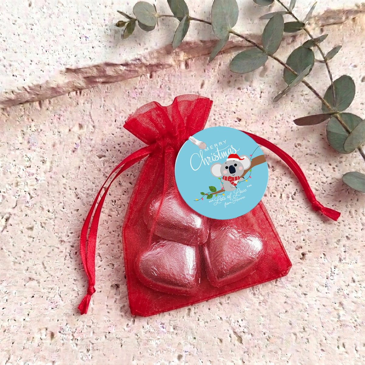 Red heart chocolates in sheer red organza drawstring gift bag with round label