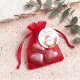 Red organza gift bag with red heart-shaped chocolates and red pull-tie ribbon