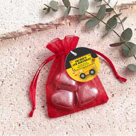 Red organza gift bag with two red heart-shaped chocolates and a black gift tag.