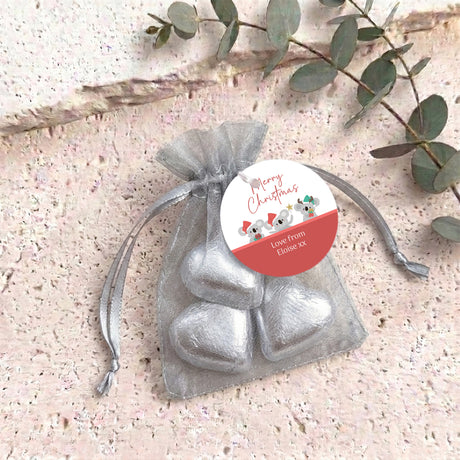 White organza gift bag with silver heart-shaped chocolates and a round gift tag