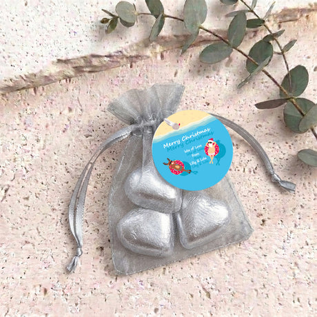 Silver metallic heart-shaped treat in clear organza drawstring bag with blue round tag