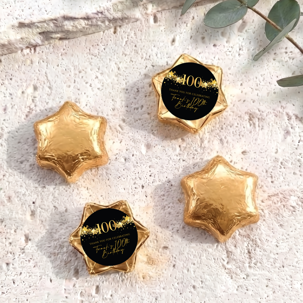 Gold foil-covered chocolate star sweets with a 100th birthday printed center