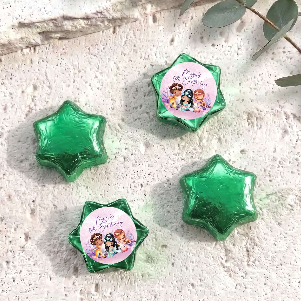 Green foil-covered chocolate stars, with a colorful mermaid birthday label star