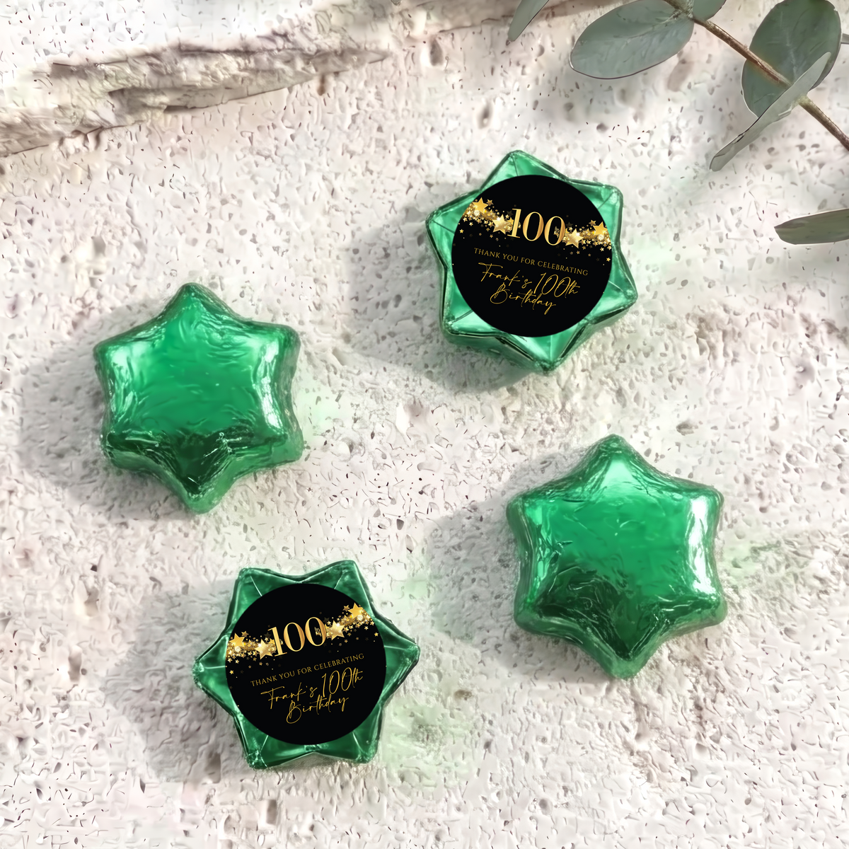 Green foil-covered chocolate star sweets with a 100th birthday printed center