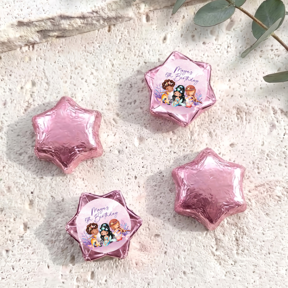 Pink foil-covered chocolate stars, with a colorful mermaid birthday label star