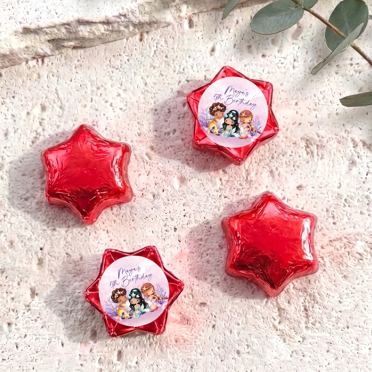 Red foil-covered chocolate stars, with a colorful mermaid birthday label star