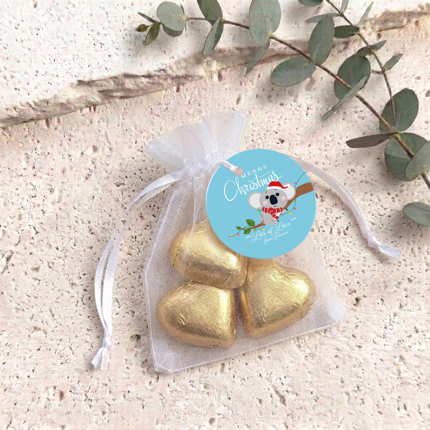 Gold heart chocolates in sheer white organza drawstring gift bag with round label
