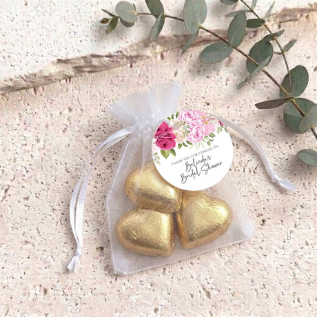 Gold heart chocolates in white organza gift bag with pink floral round label