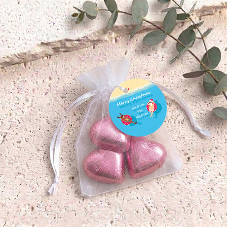 Pink metallic heart-shaped treat in clear organza drawstring bag with blue round tag