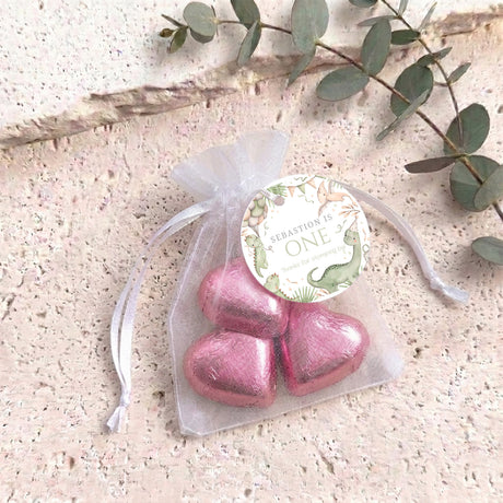 Personalised organza gift bag with dinosaur “ONE” card, pink metallic heart-shaped treats