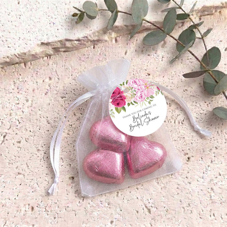 Pink heart chocolates in white organza gift bag with pink floral round label