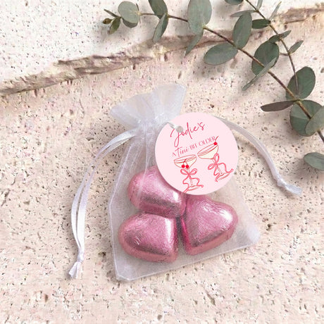 Pink metallic organza gift bag with drawstring, filled with heart-shaped chocolates