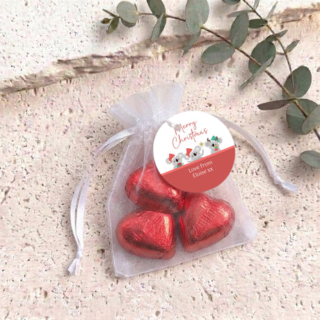White organza gift bag with red heart-shaped chocolates and a round gift tag