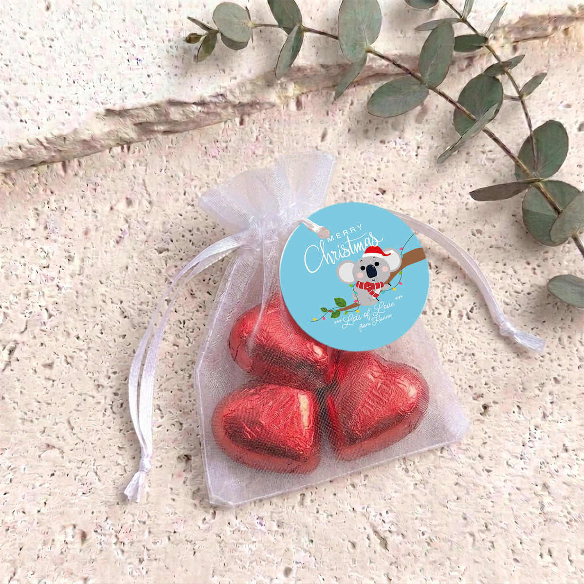 Red heart chocolates in sheer white organza drawstring gift bag with round label