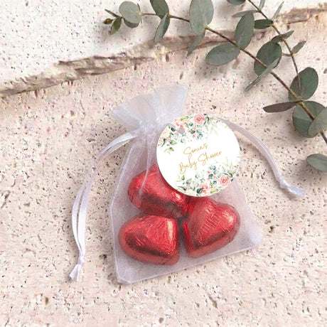Organza favor bag with red foil heart chocolates and a round floral label