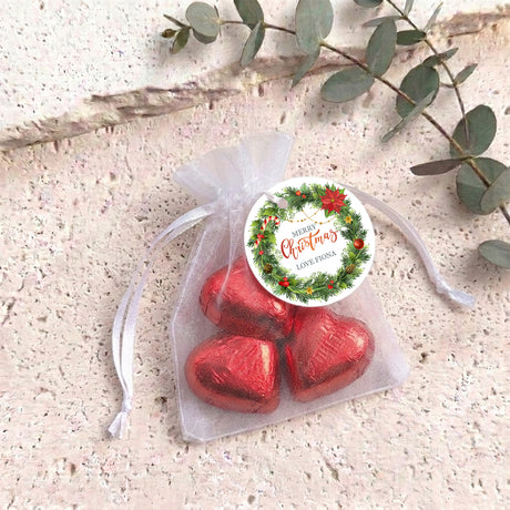 Personalised organza gift bag with red heart-shaped chocolates and round Christmas label