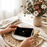 Favour Perfect personalised black and gold wedding chocolate bar held at a table setting with floral centerpiece.