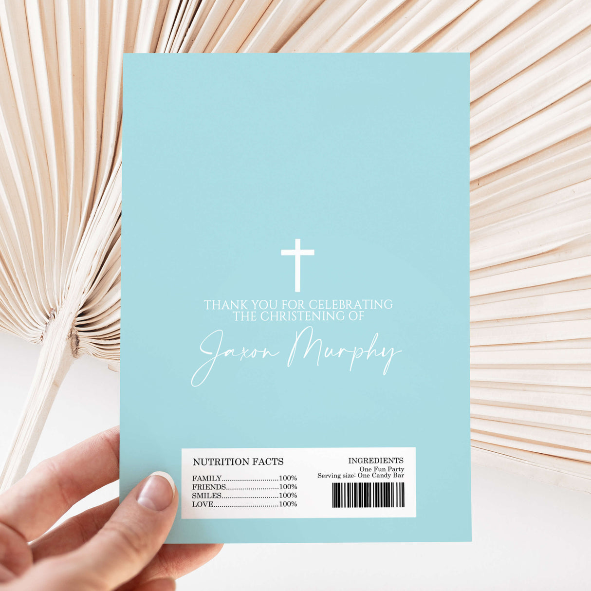Light blue christening chocolate wrapper with white cross, names, and barcode text