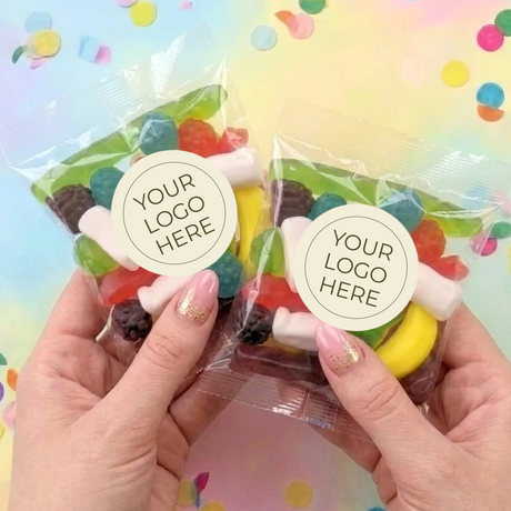 Two personalised lolly bags held in hands, each with YOUR LOGO HERE label and mixed sweets