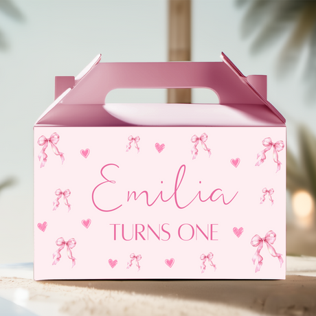 Pink gable favour box with bows, hearts, and custom text Emilia, “TURNS ONE”